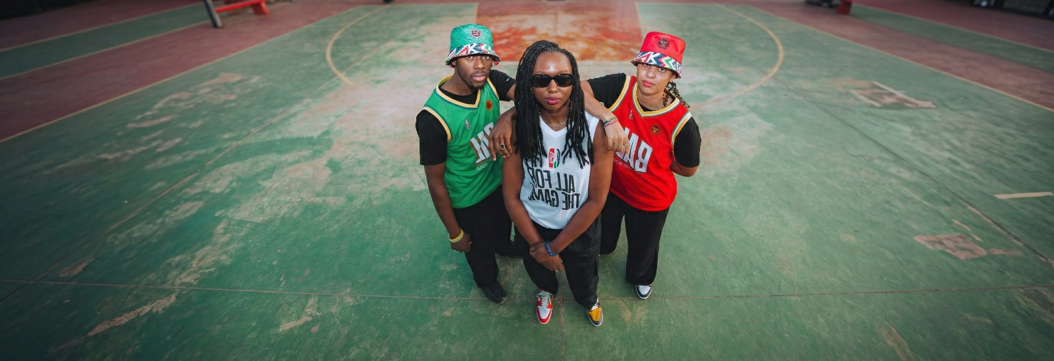 Three people posing on a basketball court with colorful outfits